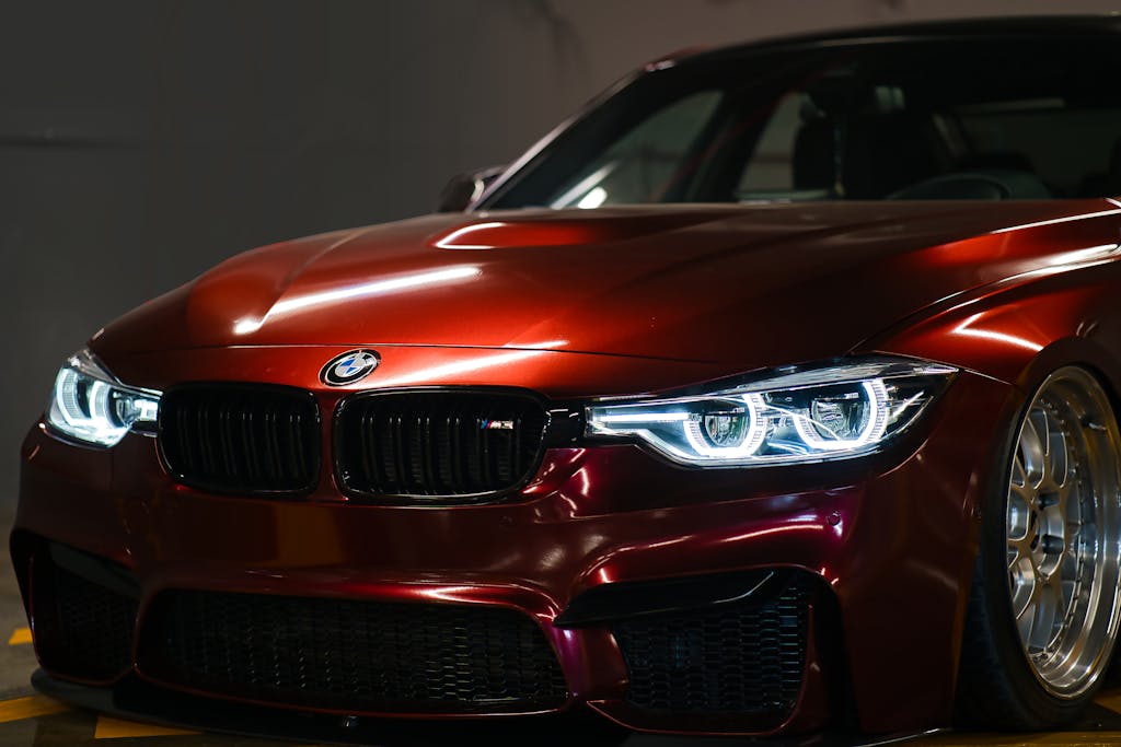 Close-up of a luxury red BMW with a sleek, shiny hood captured indoors.